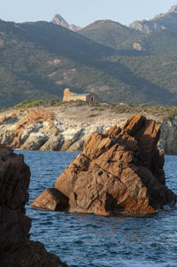 Rock formations by sea against mountain