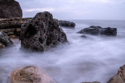 Scenic view of rocks in sea against sky