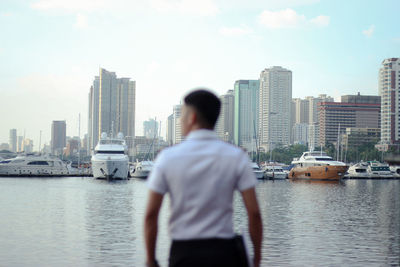 Rear view of man standing on city by buildings against sky