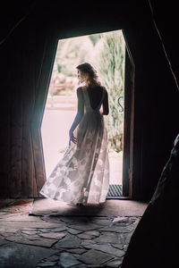 Rear view of woman standing by window