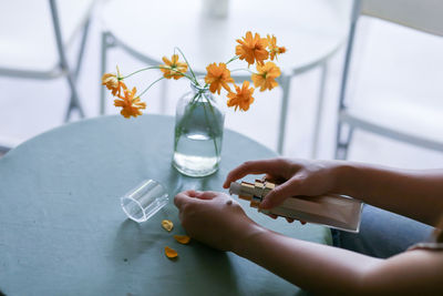 Cropped hand of woman holding bottle on table