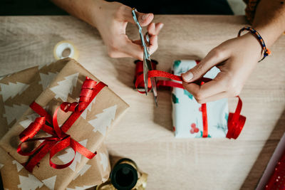 Cropped hand of man cutting ribbon while sitting at desk