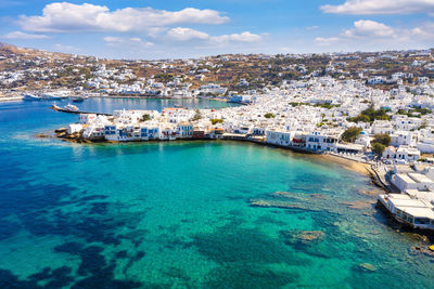 Aerial view of townscape by sea against sky