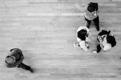 High angle view of friends sitting on hardwood floor