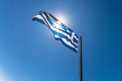 Low angle view of flag against blue sky