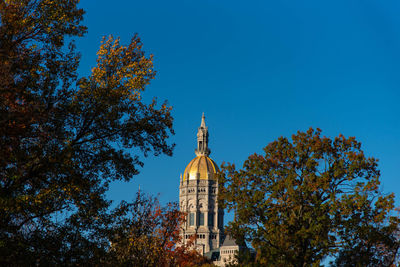 Low angle view of trees and building against sky