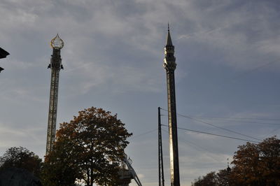 Low angle view of communications tower and building against sky