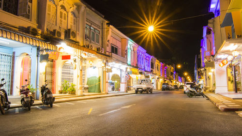 City street by illuminated buildings at night