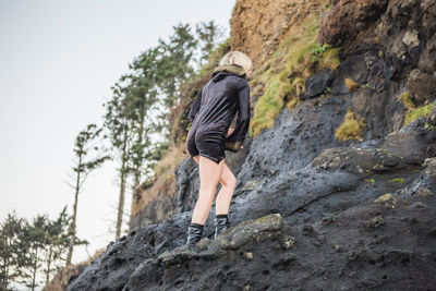 Low section of woman standing on cliff against mountain