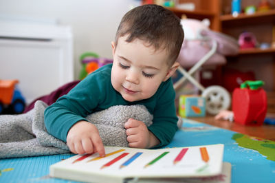 Young toddler boy looking at books and playing in his room