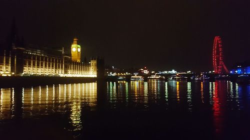 Illuminated buildings by river at night