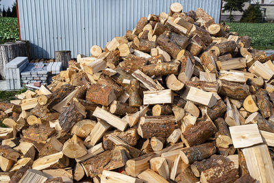 A firewood stacked in a pile, lying on the property near the metal garage, wooden background.