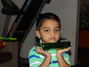 Portrait of cute boy holding camera at home