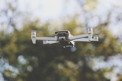 Low angle view of drone against trees