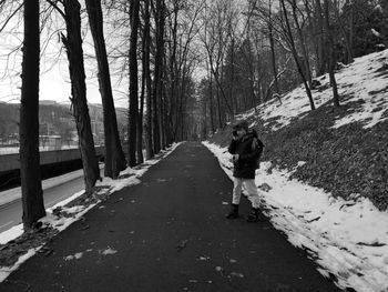 People walking on road amidst bare trees during winter