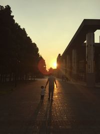 Father and son walking on street in city at sunset