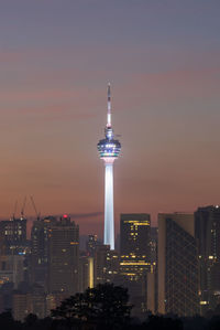 Illuminated buildings in city against sky during sunset