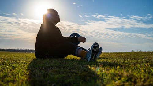Woman lying on field against sky during sunset