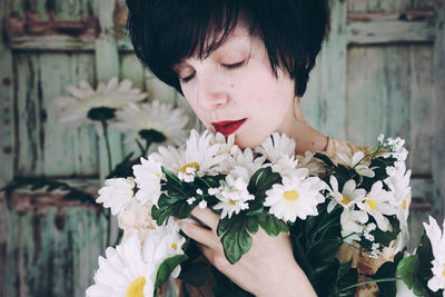 Close-up of smiling woman embracing flowers