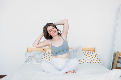 Young woman sitting on bed