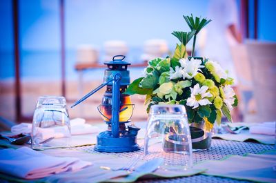 Close-up of flower vase and lantern on dinning table