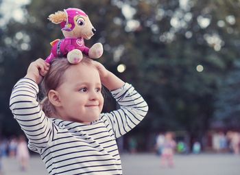 Close-up of cute smiling girl with toy standing in park