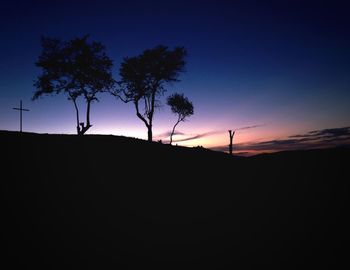 Silhouette trees on landscape against clear sky at sunset