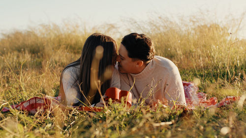 Couple lying on the grass is kissing each other