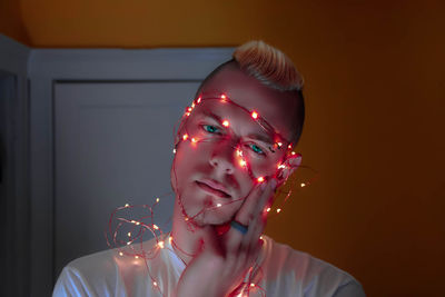 Close-up of fairy lights wrapped around man