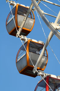 Closeup of colorful cabins of giant ferris wheel in amusement park against blue sky