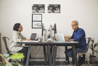 Senior male and female colleagues working on computer in office