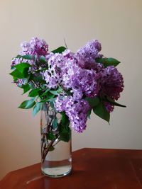 Close-up of purple flower vase on table against wall