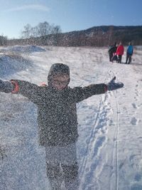 Rear view of boy on snow covered landscape during winter