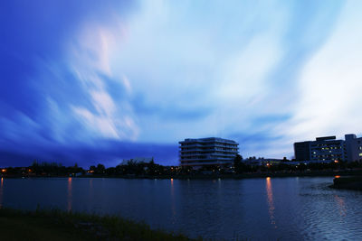 City by lake against sky at dusk