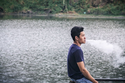 Side view of young man looking away in lake