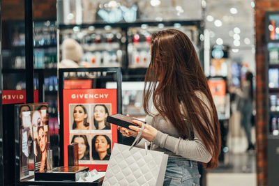 Woman standing on mobile phone at store