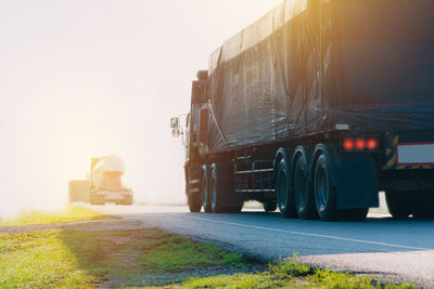 Trucks on road against clear sky