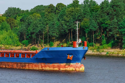 Boat moored in river against trees