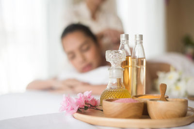 Close-up of spa product against young woman lying on massage table