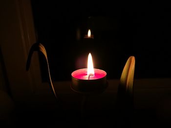 Close-up of illuminated tea light candles in darkroom