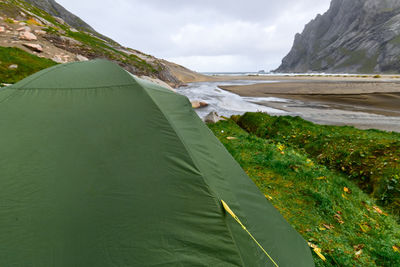 Green tent on a green grass hill at bunes beach with view over the valley in lofoten norway