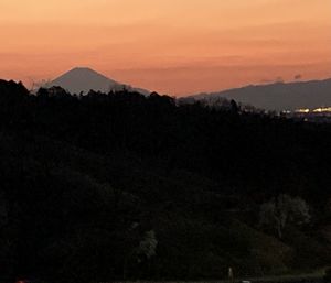 Scenic view of silhouette mountains against orange sky