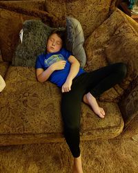 High angle view of boy relaxing on sofa at home