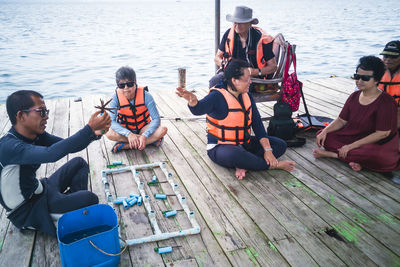 People sitting on deck chairs at sea shore