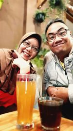 Portrait of smiling woman with drink on table at restaurant