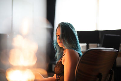 Side view of young woman sitting on chair