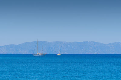 Tow sailing boats in ocean,in the background mountains.