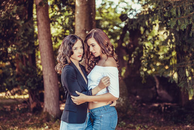 Beautiful young women standing against trees in forest