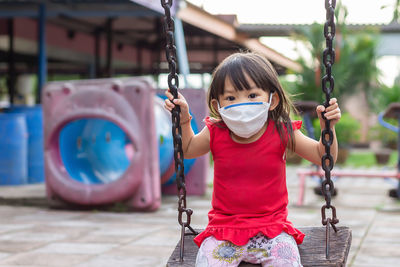 Portrait of cute girl sitting on swing in playground