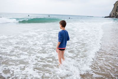 Rear view of boy standing at beach